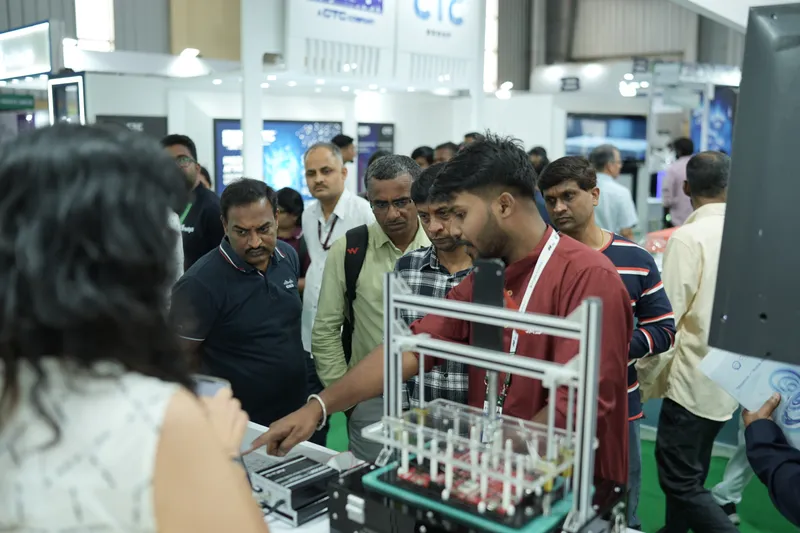 Visitors gather round a board test fixture on the GSAS stand at electronica India 2026